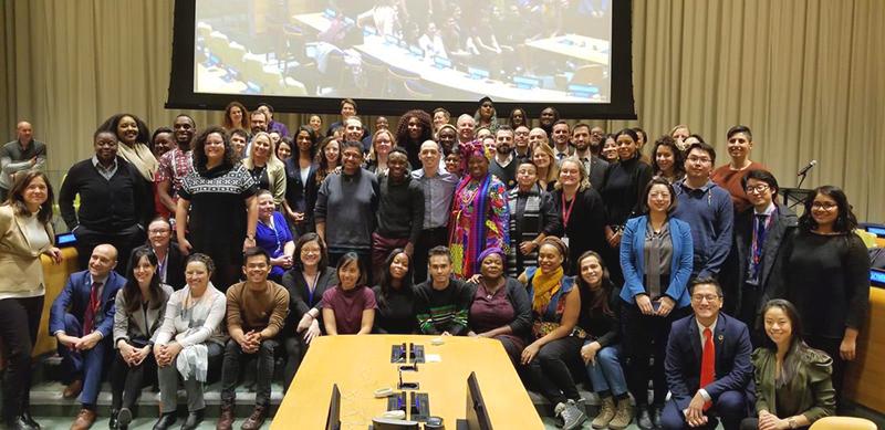 A group of people posing together in front of a projection at the United Nations